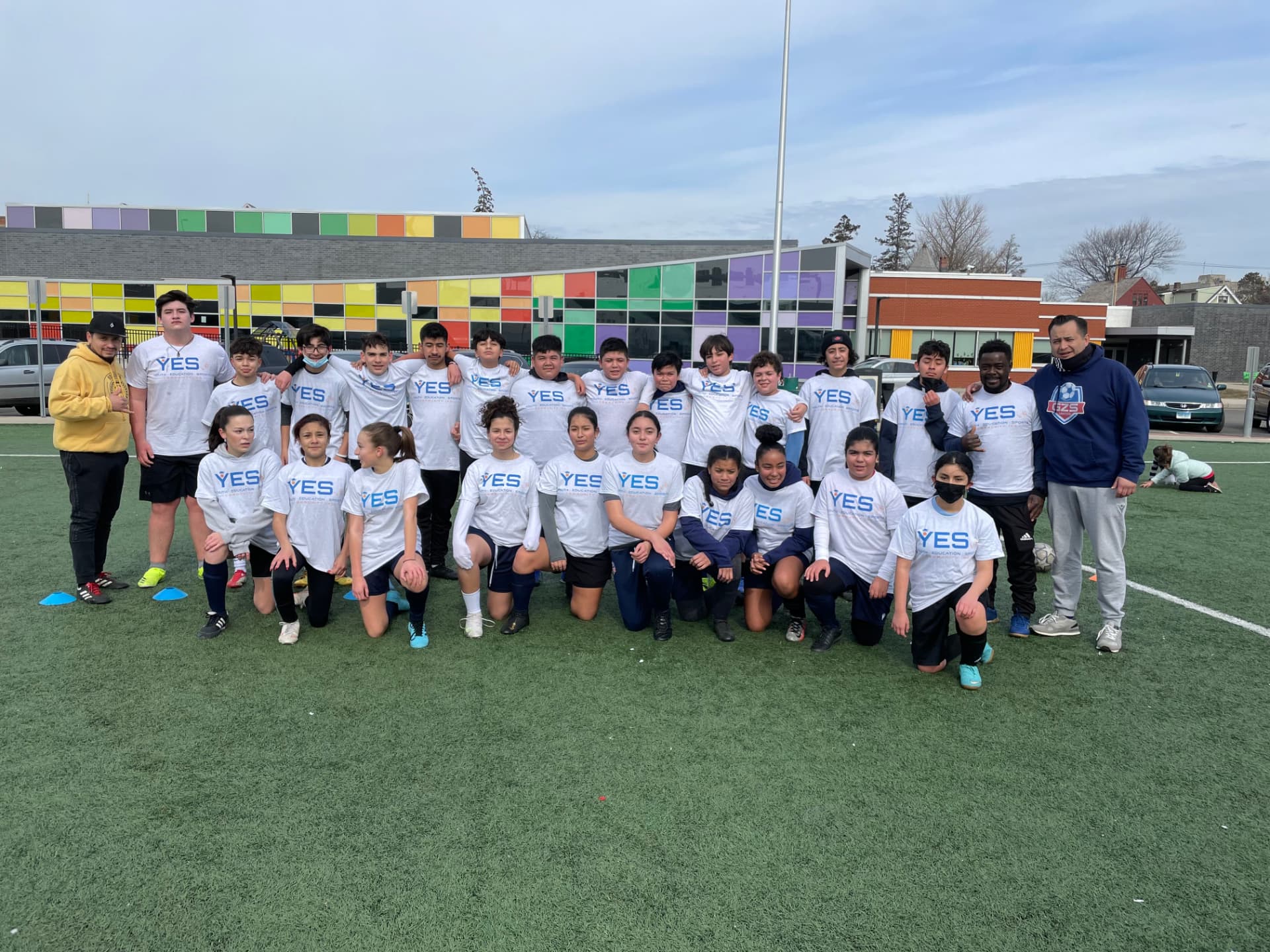 Teen players in YES shirts gathered on the turf after practice