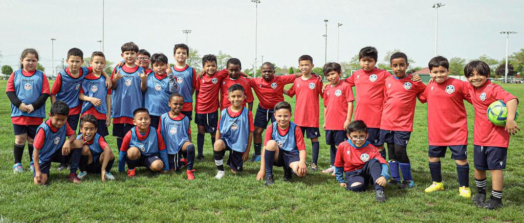 A YES youth soccer team in red and blue kits posing on the field