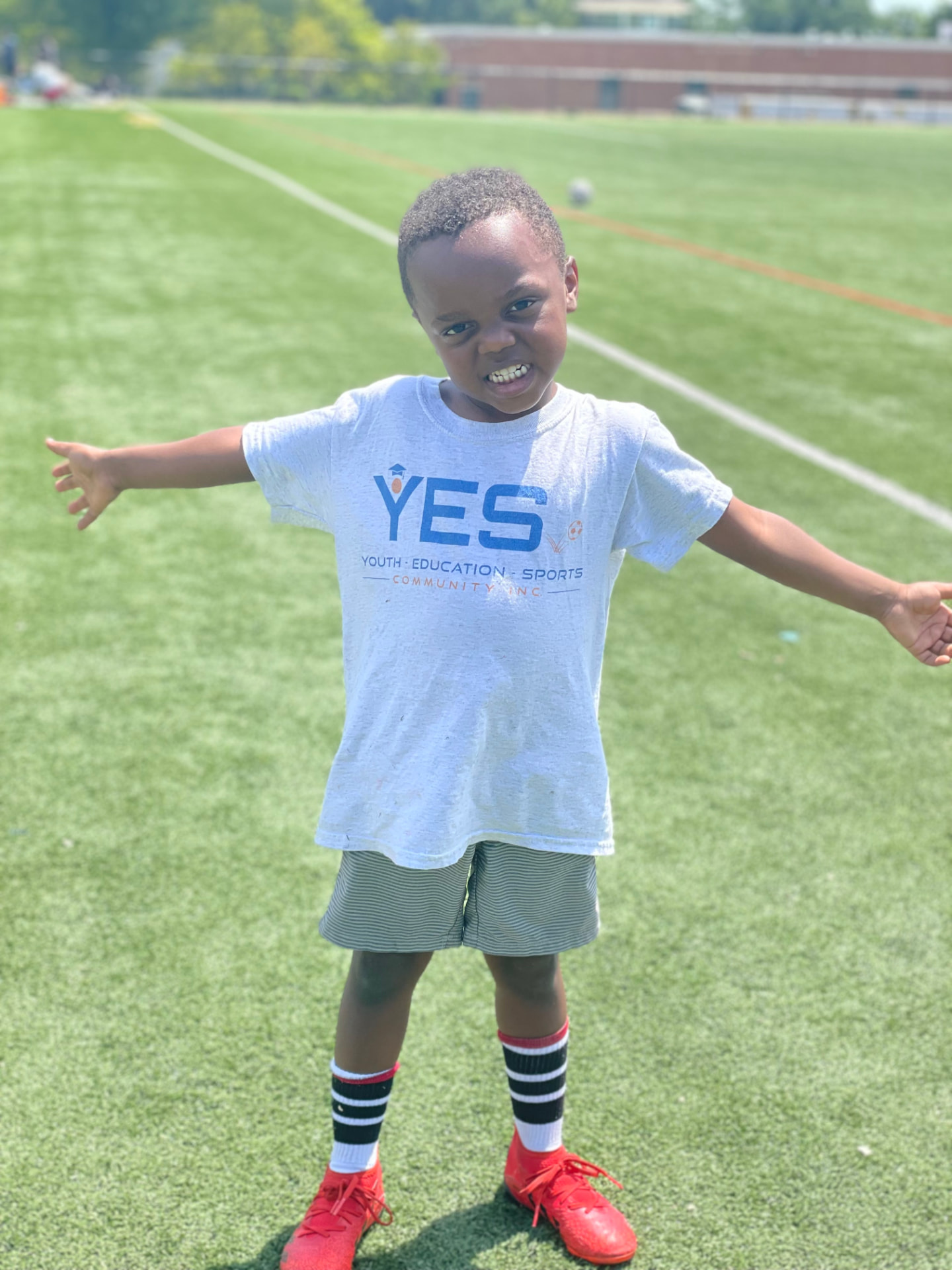 A young player in a YES t-shirt with arms outstretched on the field